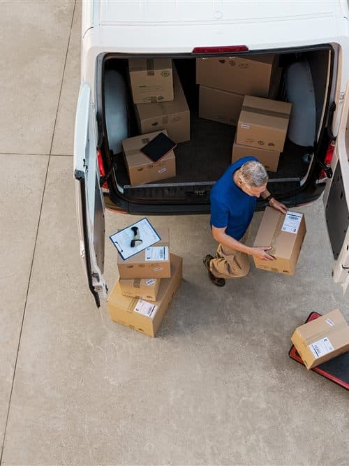 Repartidor descargando paquetes de la furgoneta de reparto de una empresa de mensajería